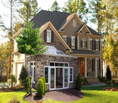 The exterior of a two-story, brick home with the sunroom doors opening to the yard.